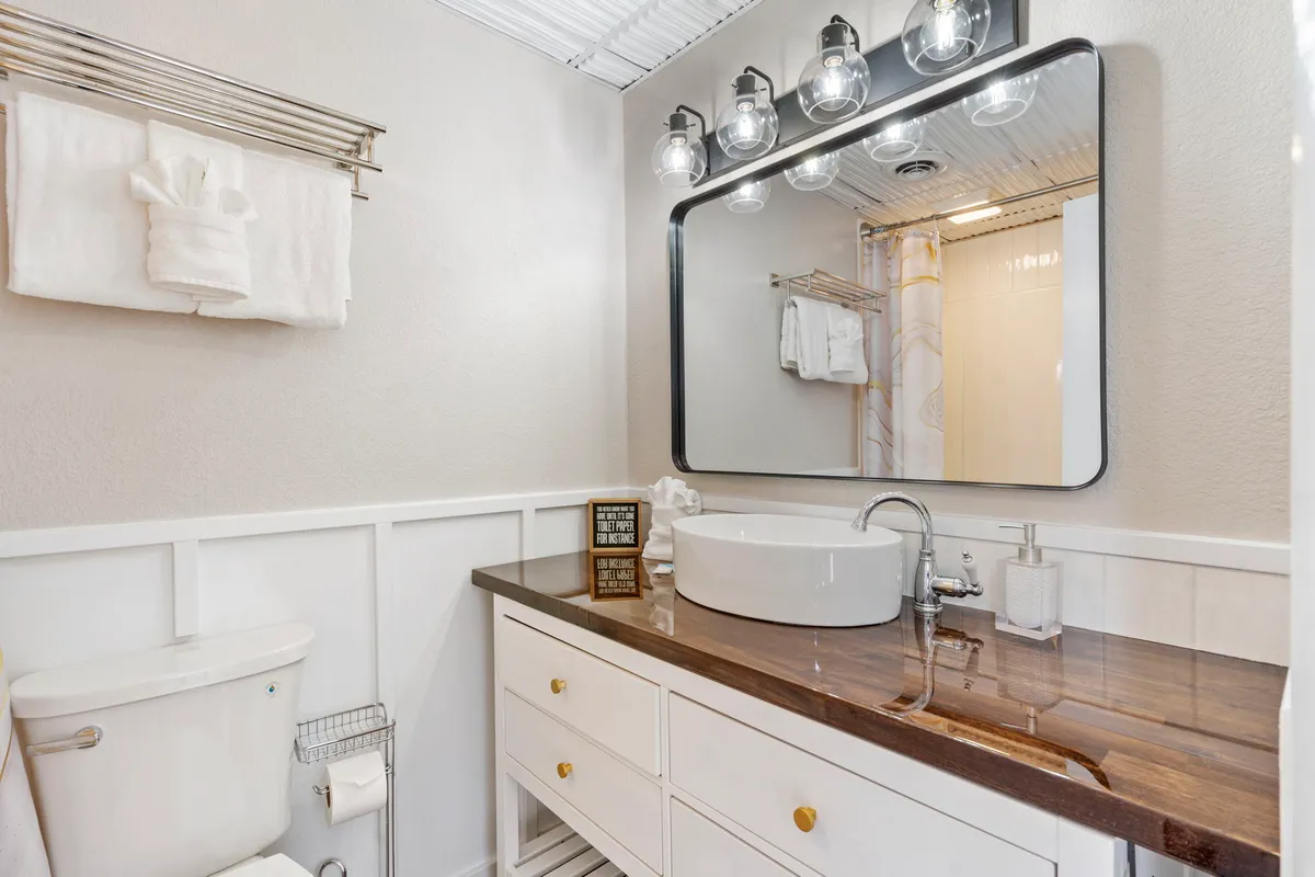 A stylish bathroom vanity with double sinks, a large mirror, and attractive lighting fixtures. The clean design and subtle decor evoke a spa-like feel, ideal for self-care and relaxation.