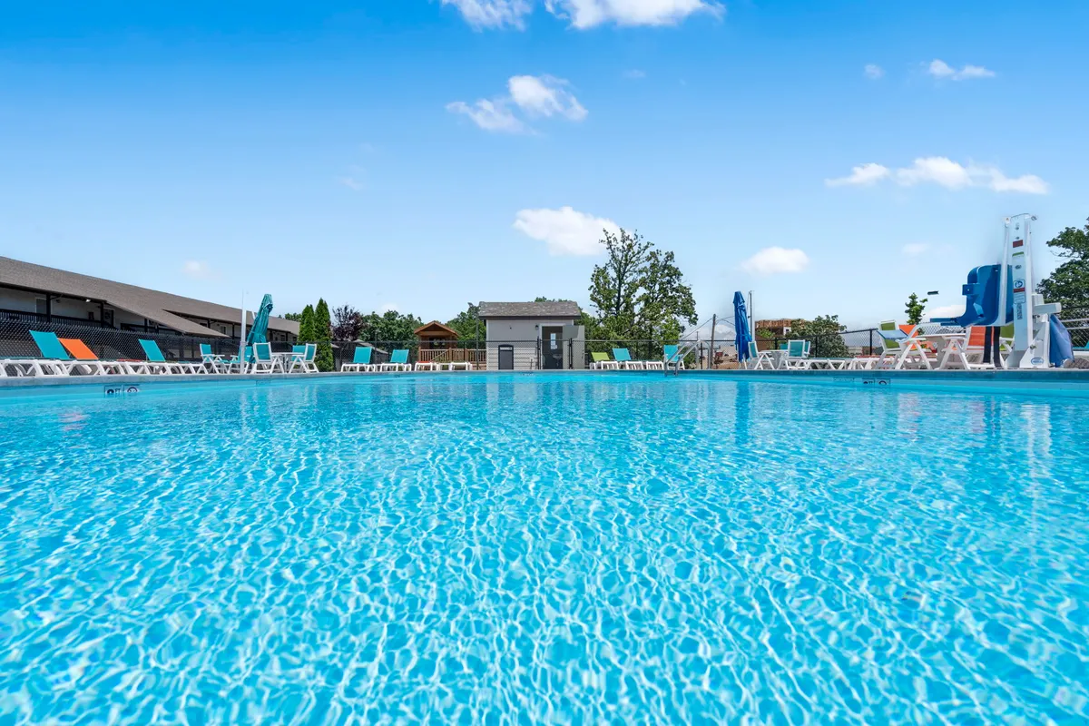 An inviting outdoor pool scene, with colorful lounge chairs, a slide, and a lifeguard station, buzzing with social activity and perfect for sun-soaked afternoons.