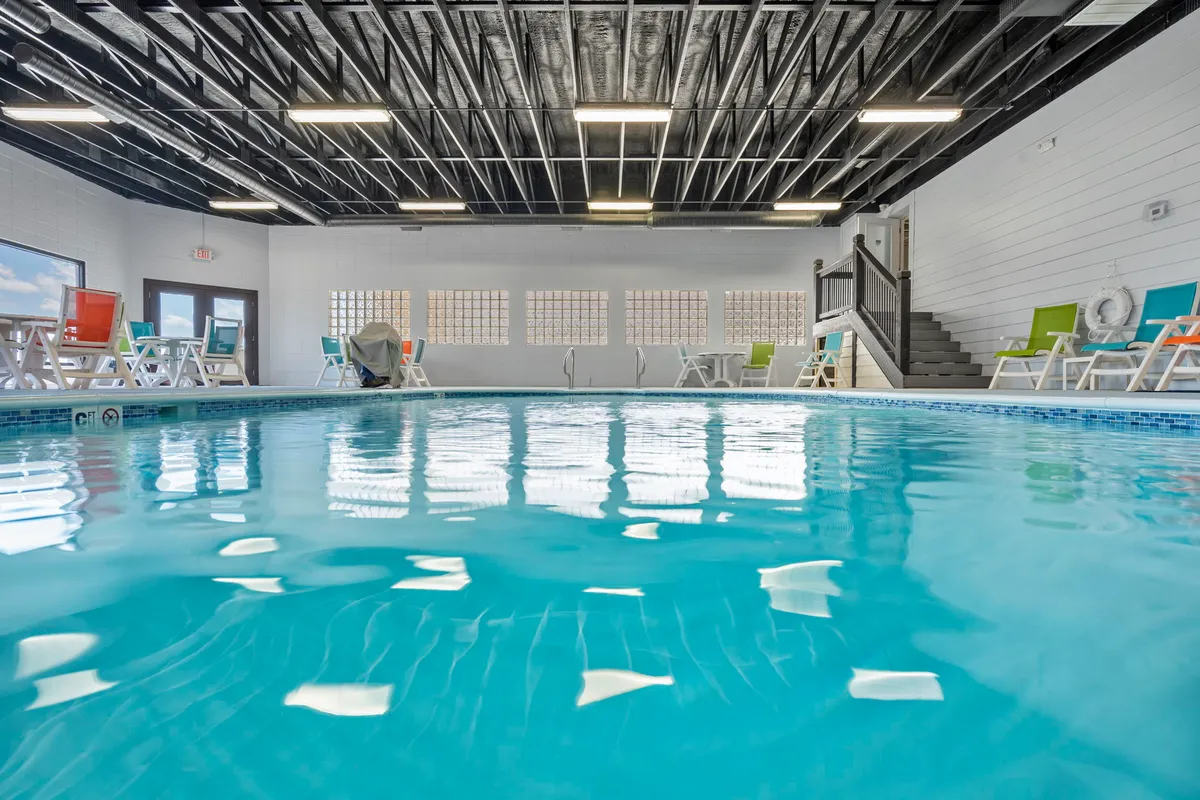 An inviting indoor swimming pool surrounded by colorful lounge chairs and radiant natural light. The pool area is set up for relaxation and casual socializing, with a soothing atmosphere perfect for unwinding together after a day of adventure.