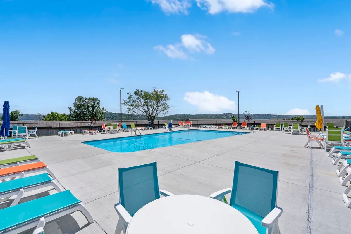 An inviting outdoor swimming pool surrounded by colorful lounge chairs and lush greenery, creating a cheerful and relaxed atmosphere perfect for group gatherings and sunny afternoons.