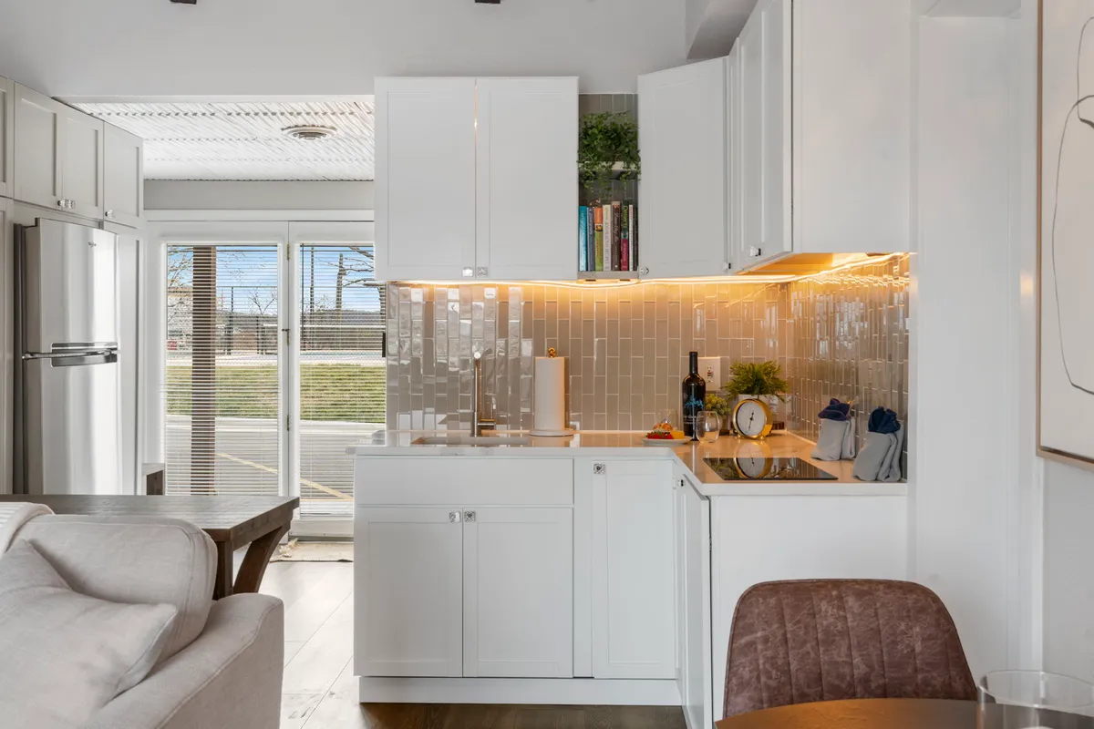 A contemporary kitchen scene showcasing attractive cabinets, ample countertop space, a decorative backsplash, and a dining table positioned for easy interaction. The setting invites cooking, entertaining, and casual dining in a cozy, central hub.