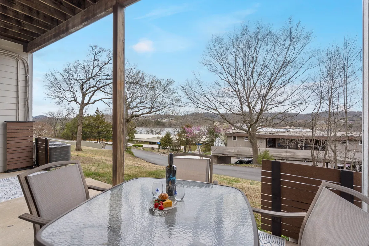 A table set with wine and snacks positioned outdoors, offering a scenic view of the landscape with bare trees and distant houses. The setup suggests moments of peaceful enjoyment, whether for coffee in the morning or drinks at sunset.